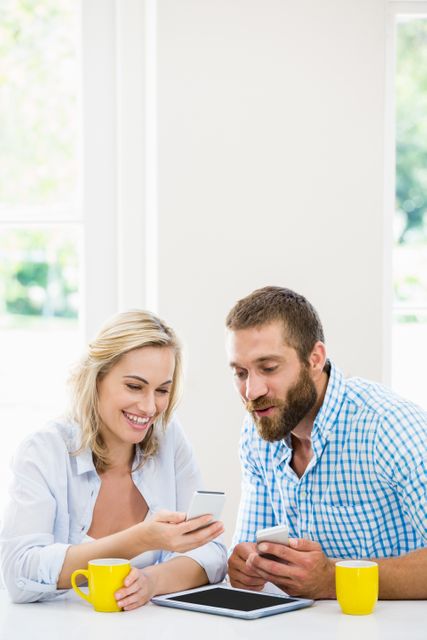 Smiling couple using a mobile phone at home