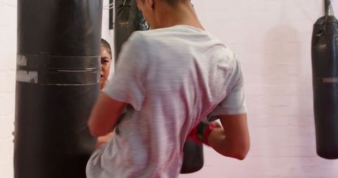 Boxer delivering kicks and punches while partner bracing heavy bag in gym drill