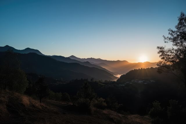 Image depicts sunrise over a mountain valley with misty hills in the background. Ideal for travel blogs, nature websites, meditation and wellness retreat advertisements, outdoor adventure promotion, and inspirational posters emphasizing serenity and natural beauty.
