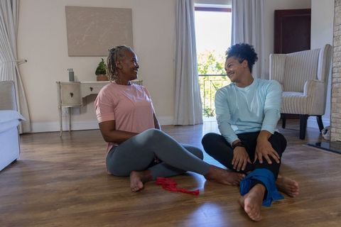 Practicing seated resistance band stretches: senior woman and younger man sharing workout