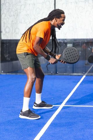 Athletic Man with Dreadlocks Ready to Play Padel on Vibrant Blue Court