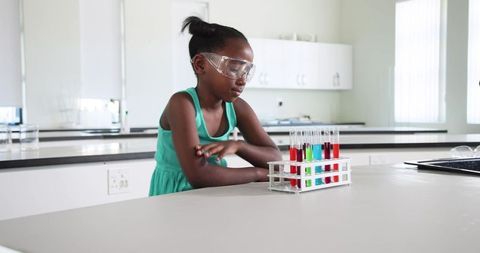 African American Teen Conducting Colorful Chemistry Experiment in Bright School Laboratory