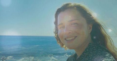 Smiling Woman Enjoying Coastal Sunlit Breeze by Ocean