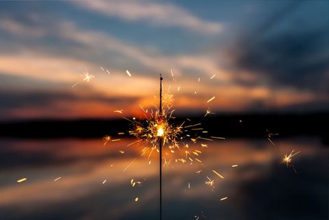 Sparkler illuminating at sunset over water's horizon