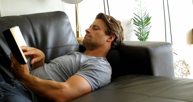 Man Relaxing on Sofa Reading a Book in Modern Living Room - Download Free Stock Images Pikwizard.com