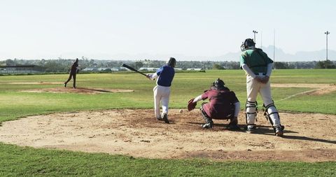 Young man batting on baseball field swing at pitch, competitive team sport