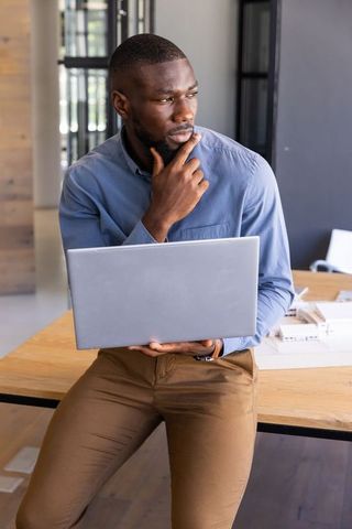 Professional Businessman Holding Laptop in Modern Office Environment