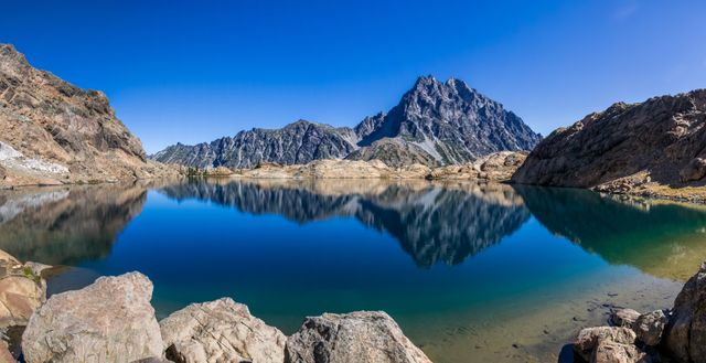 Pristine Mountain Lake Reflecting Rocky Peaks Under Clear Blue Sky - Download Free Stock Photos Pikwizard.com