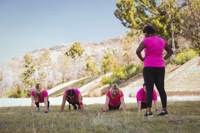 Female trainer leading a group of women in an outdoor boot camp session on a sunny day. Ideal for use in fitness blogs, health and wellness websites, promotional materials for fitness programs, and advertisements for outdoor exercise classes.