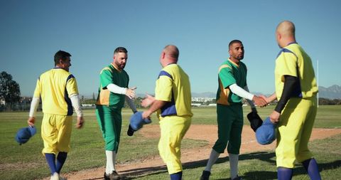 Baseball players exchanging handshakes and caps on sunny diamond after game