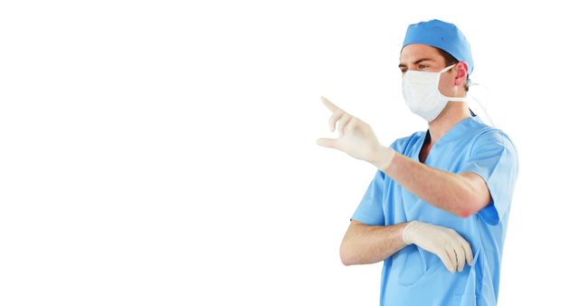 A surgeon wearing blue scrubs, a face mask, and gloves pointing towards something, signifying involvement in a surgical procedure. The white background emphasizes the sterile, professional setting, often used in medical and healthcare advertisements, educational materials, and hospital promotions.