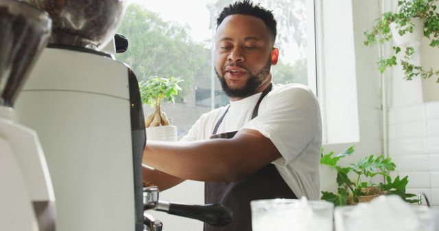 Happy african american male barista making coffee using coffe machine at cafe. small independent cafe business.