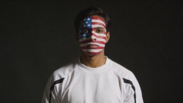 Patriotic portrait of man wearing american flag face paint and white athletic sweatshirt
