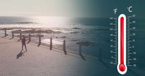 Digital thermometer over coastal path with jogger amid ocean view