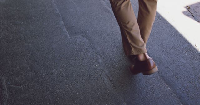Low section of caucasian businessman wearing brown shoes walking on street, copy space. Lifestyle, business and city, unaltered.