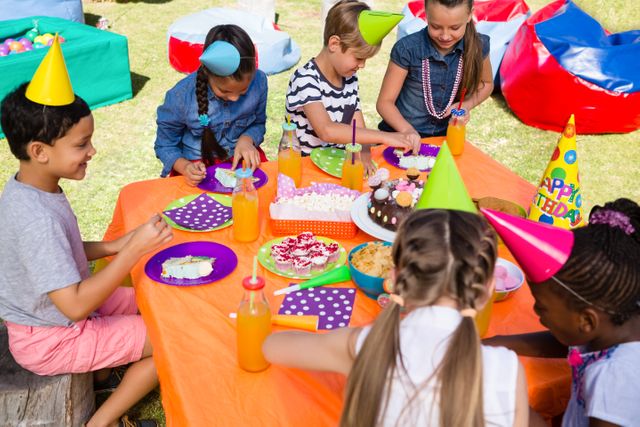 Children gathered around table at outdoor birthday party, wearing colorful party hats, enjoying treats and drinks. Perfect for depicting celebrations, children's parties, social events, festive gatherings, and family-friendly activities.
