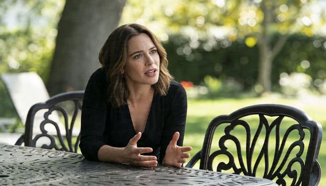 Brunette woman leaning and gesturing during outdoor conversation at ornate metal patio table