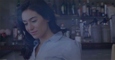 Smiling Bartender Organizing Glassware Behind Cozy Bar