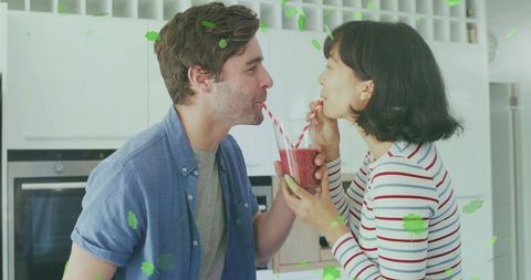 Couple sharing berry smoothie with red-striped straws in bright kitchen
