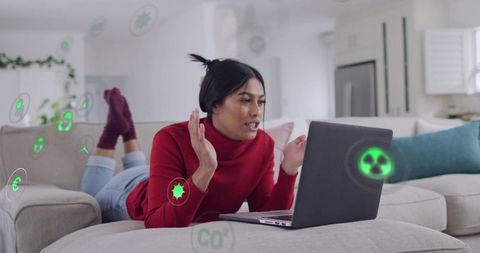 Woman gesturing during video calling on laptop with augmented reality icons for remote work