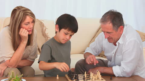 Young Boy Playing Chess with Grandparents at Home