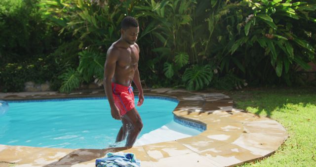 Handsome african american man walking out of in swimming pool in sunny garden - Download Free Stock Photos Pikwizard.com
