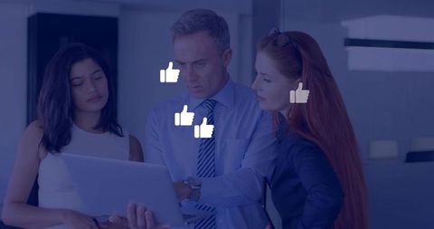 Business team collaborating over laptop reviewing social media likes and analytics