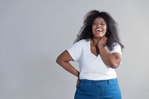 Laughing woman wearing v-neck top and denim jeans with headband and hoop earrings
