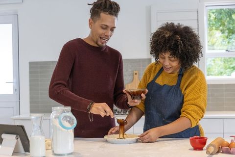 Couple baking chocolate pie together in bright modern kitchen showing teamwork and joy