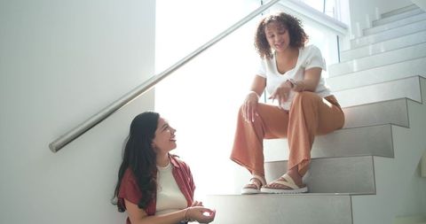 Diverse friends chatting on bright modern stairwell showing casual watch and relaxed vibe