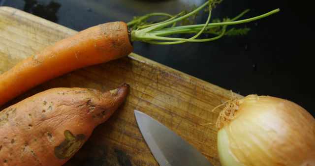Close-up of onion, carrot and sweet potato with knife at home 4k