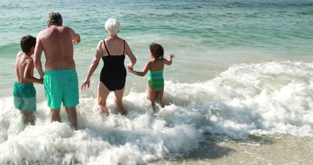 Grandparents and grandchildren are playing in ocean waves at the beach. They are spending quality family time on a summer vacation. This image is suitable for promoting family holidays, beach activities, travel destinations, and outdoor family fun. Can be used in articles about multigenerational travel, family bonding moments, and healthy outdoor activities.