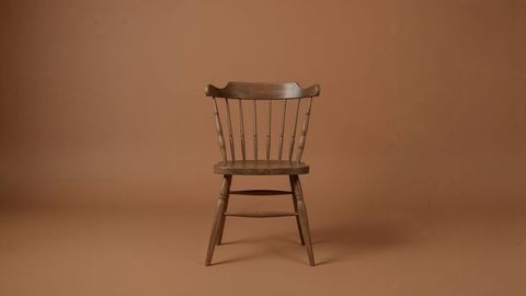 Rustic wooden chair with spindle back on brown backdrop