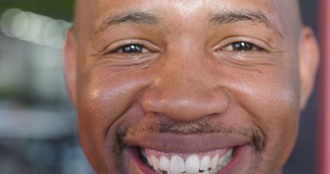Warm African American man smiling closeup showing teeth joyful headshot with bokeh