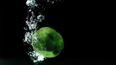 Green Bell Pepper Dropping into Water with Bubbling Effect