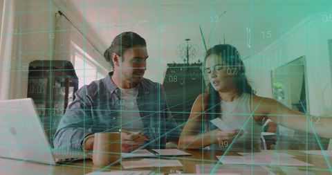 Couple Reviewing Finances at Home Dining Table with Teal Digital Data Overlay