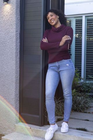 Stylish Woman Relaxing at Modern Home Entrance with Vibrant Lens Flare