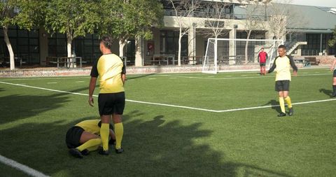 Caring Soccer Players Supporting Injured Teammate on Field