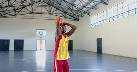 Basketball Player Practicing Shot Indoors in School Gym