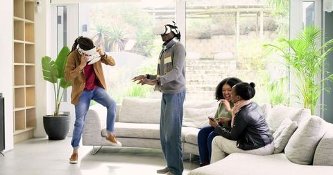 Friends Experiencing Virtual Reality Laughing Together in Bright Living Room