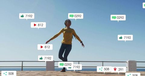 Woman in Yellow Top Balancing on Seaside Railing with Media Icons