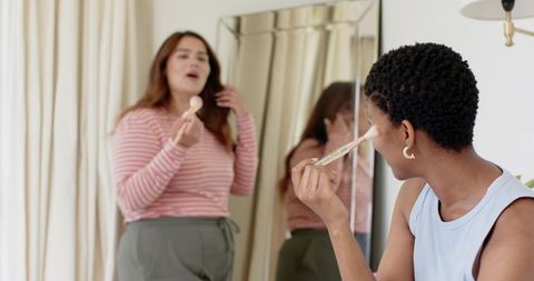 Two women applying makeup at mirror sharing beauty routine and friendship