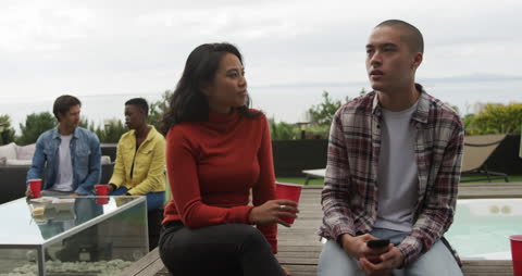 Group of Friends Relaxing on Rooftop Terrace with Drinks on a Cloudy Day