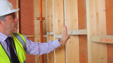 Architect Inspecting Wooden Structures at Construction Site
