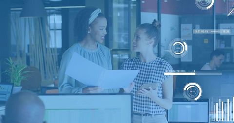 Collaborating women reviewing data reports with tablet in open office with hud overlays