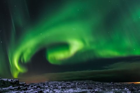 Aurora Borealis Dancing Over Snowy Rocky Coastline Under Starry Sky