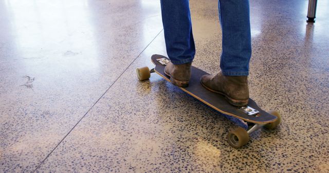 Person balancing on longboard while wearing boots, showing casual and relaxed lifestyle. Ideal for concepts related to skateboarding culture, leisure activities, or trendy urban footwear. Useful for articles, ads, or social media posts about skateboarding, casual fashion, or indoor activities.