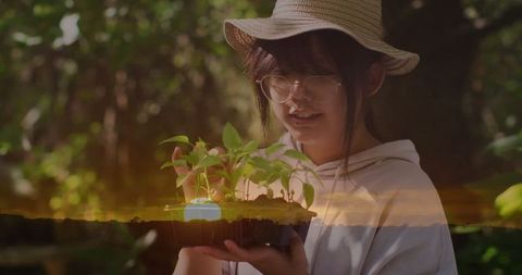 Young Woman Examining Plant Seedlings in Garden