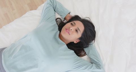Woman relaxing on bed in minimalist bedroom ambiance
