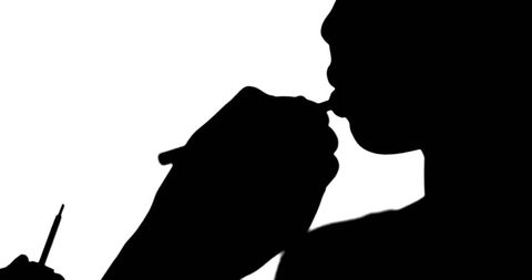 Silhouette of makeup artist applying lip gloss to model